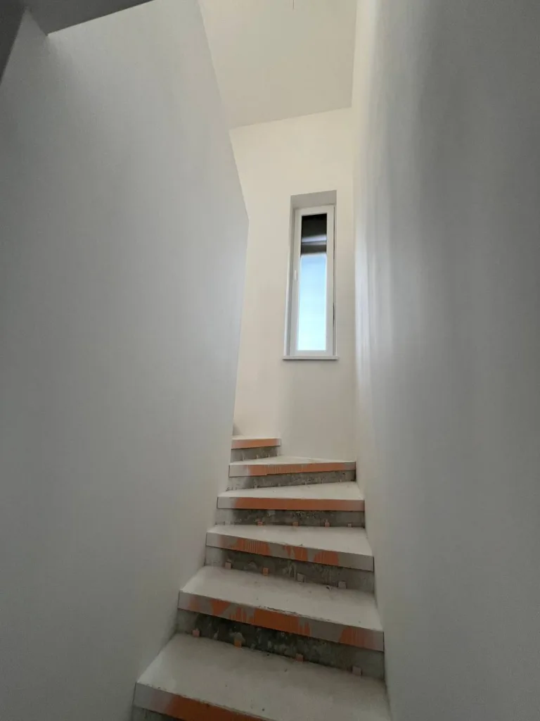 Vymaľované schodisko s oknom v rodinnom dome
